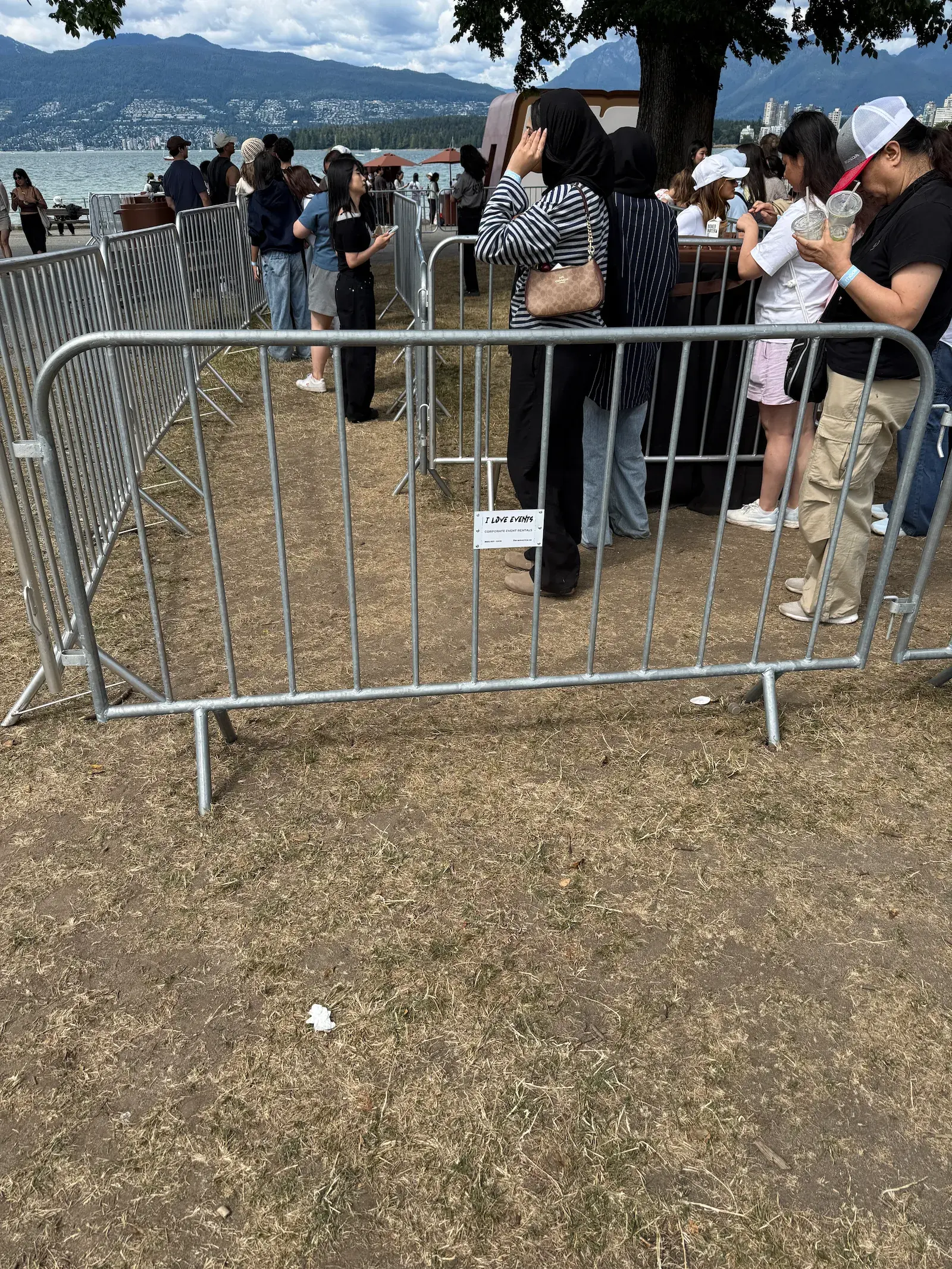 Crowd control barriers forming a line along a waterfront event site with mountains behind.